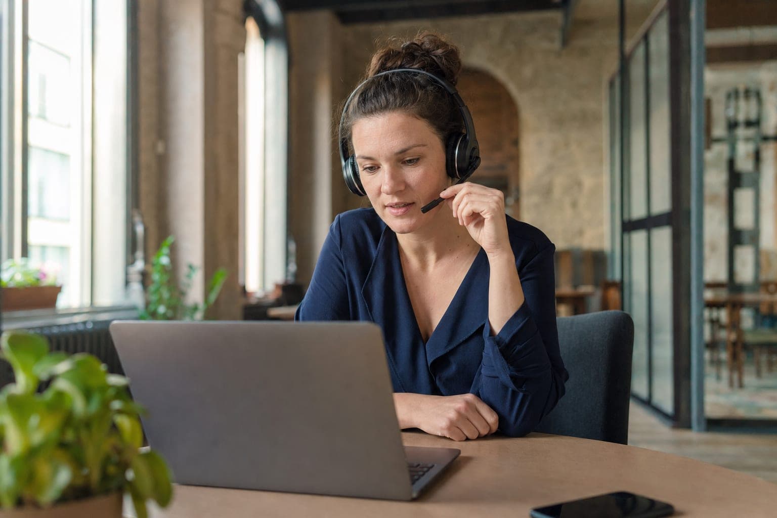 Mitarbeiterin telefoniert konzentriert am Schreibtisch